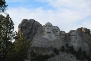 Four colossal presidential sculptures, George Washington, Thomas Jefferson, Theodore Roosevelt, and Abraham Lincoln, carved into the granite face of Mount Rushmore in South Dakota.